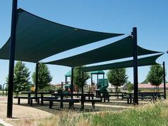 an outdoor play area with benches and shade sails