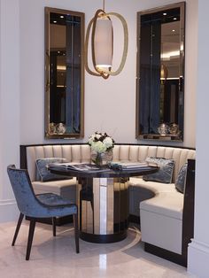 a corner table with two chairs and a bench in front of mirrors on the wall