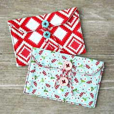 two red and white envelopes sitting next to each other on a wooden surface with buttons