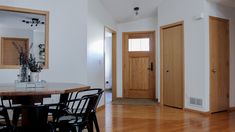 a dining room table and chairs in front of a door with a mirror on the wall