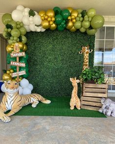 an animal themed birthday party with balloons and greenery on the wall, jungle theme