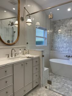 a bathroom with a tub, sink and large mirror on the wall next to it