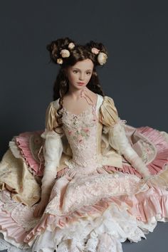 a doll sitting on top of a table wearing a dress and hairdow with flowers in her hair