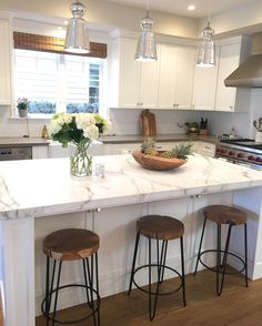 a kitchen island with three stools in front of it