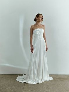 a woman in a white wedding dress standing on the floor with her arms behind her back