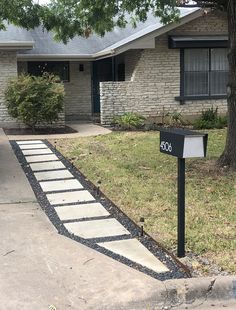 a mailbox in front of a house with a walkway leading to the door and driveway