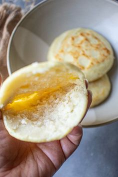 a person holding an egg in their left hand and some other food on the plate