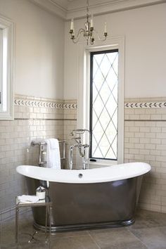 an old fashioned bathtub is in the middle of a bathroom with white tile walls and flooring