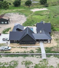 an aerial view of a large house in the middle of a field with trucks parked nearby