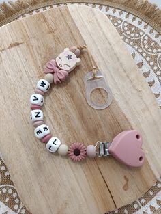 a wooden board with a keychain on it and a pink heart charm attached to it