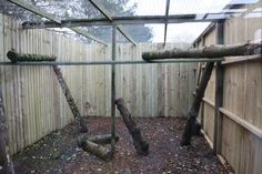 a fenced in area with some logs and branches hanging from the top of it