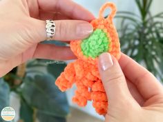 a hand holding an orange and green crocheted object