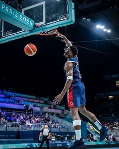 a basketball player dunking the ball in front of an arena full of people watching