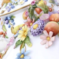 an arrangement of fruit and flowers on a plate