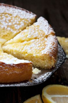 a cake with powdered sugar on it sitting on top of a plate next to sliced bananas