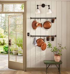 pots and pans are hanging on the wall next to a table with a bench