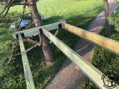 a wooden bench sitting next to a tree on top of a lush green park ground