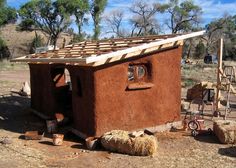 a small adobe style house with hay bales and other items around the outside area