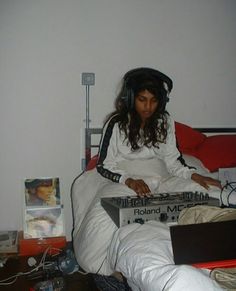 a woman sitting in bed with headphones on and looking at a box that is open