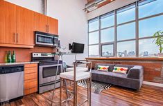 a living room filled with furniture next to a kitchen and an open floor plan in front of a large window