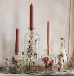 several glass bottles filled with flowers and candles