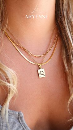 a woman wearing a gold necklace with an initial charm