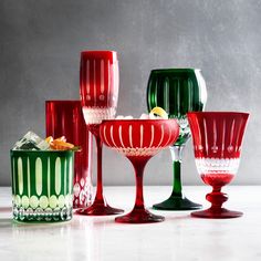 several red and green wine glasses sitting next to each other on a white counter top