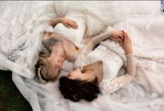 two women laying on top of each other in white wedding gowns and veils