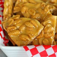 some kind of food that is in a white bowl on a red and white checkered table cloth