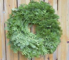 a green wreath hanging on a wooden fence