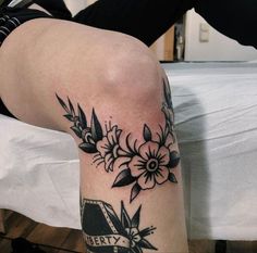 a woman's leg with black and white flowers on her left thigh, next to a bed