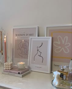 some candles and pictures on a white shelf