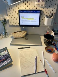 a computer monitor sitting on top of a desk next to a book and pen holder