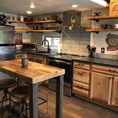 a kitchen with wooden cabinets and stainless steel appliances is pictured in this image, there are two stools at the center of the counter