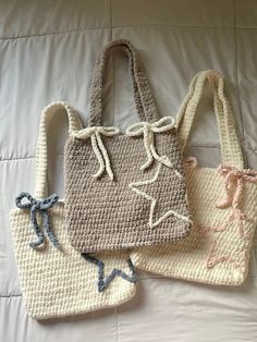 three crocheted bags sitting on top of a white bed next to each other