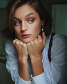 a woman with blue eyes is posing for a photo in white shirt and suspenders