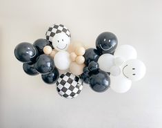 black and white balloons are arranged in the shape of a smiley face on a wall