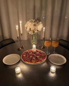 a table topped with a pizza next to two glasses of wine and plates filled with food