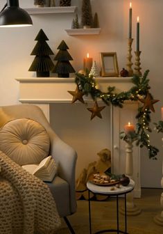 a living room decorated for christmas with candles and decorations on the fireplace mantels