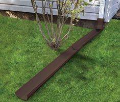 a brown gutter guard on the grass in front of a house with a tree