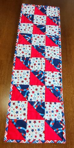 a red, white and blue quilted table runner on a wooden floor with wood floors