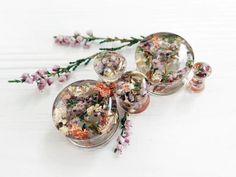 three glass vases filled with flowers on top of a white table next to each other