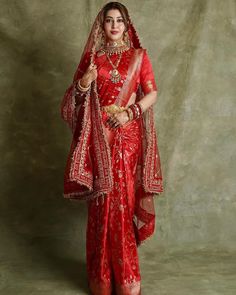 a woman in a red bridal outfit posing for the camera with her hands on her hips