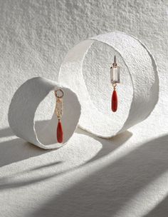 a pair of earrings sitting on top of a white circular object next to a shadow