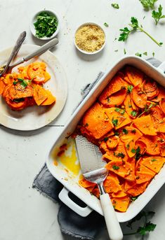 a casserole dish with carrots and parsley on the side