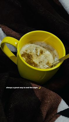 a yellow cup filled with liquid sitting on top of a blanket