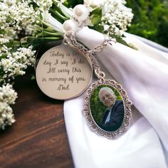 a memorial keychain with an image of a man on it and flowers in the background