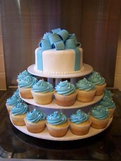 a three tiered cake with blue frosting on top and cupcakes in the bottom