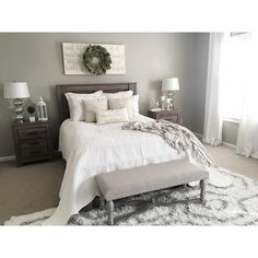 a white bed sitting in a bedroom on top of a wooden dresser next to a window