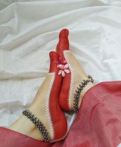 two feet in red and white socks with flowers on them, laying on a bed